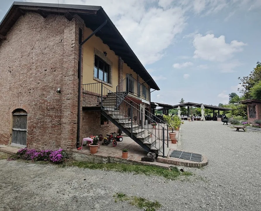 La cascina in mattoni con la scala esterna in ferro e i vasi di fiori.